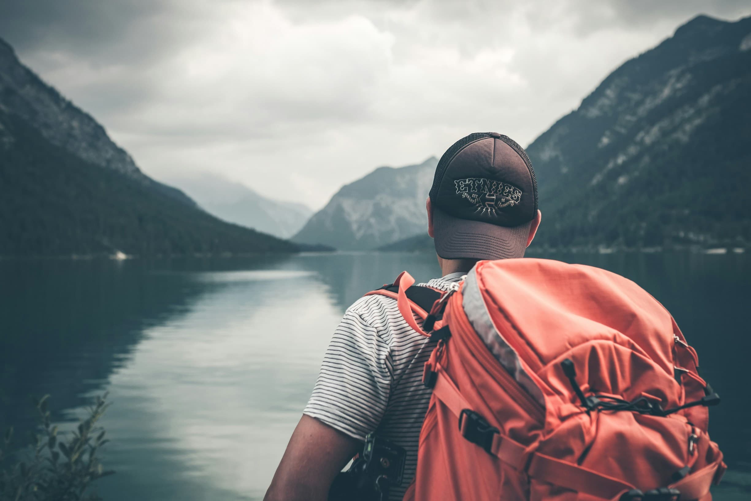 Young man with backpack overlooking mountain lake