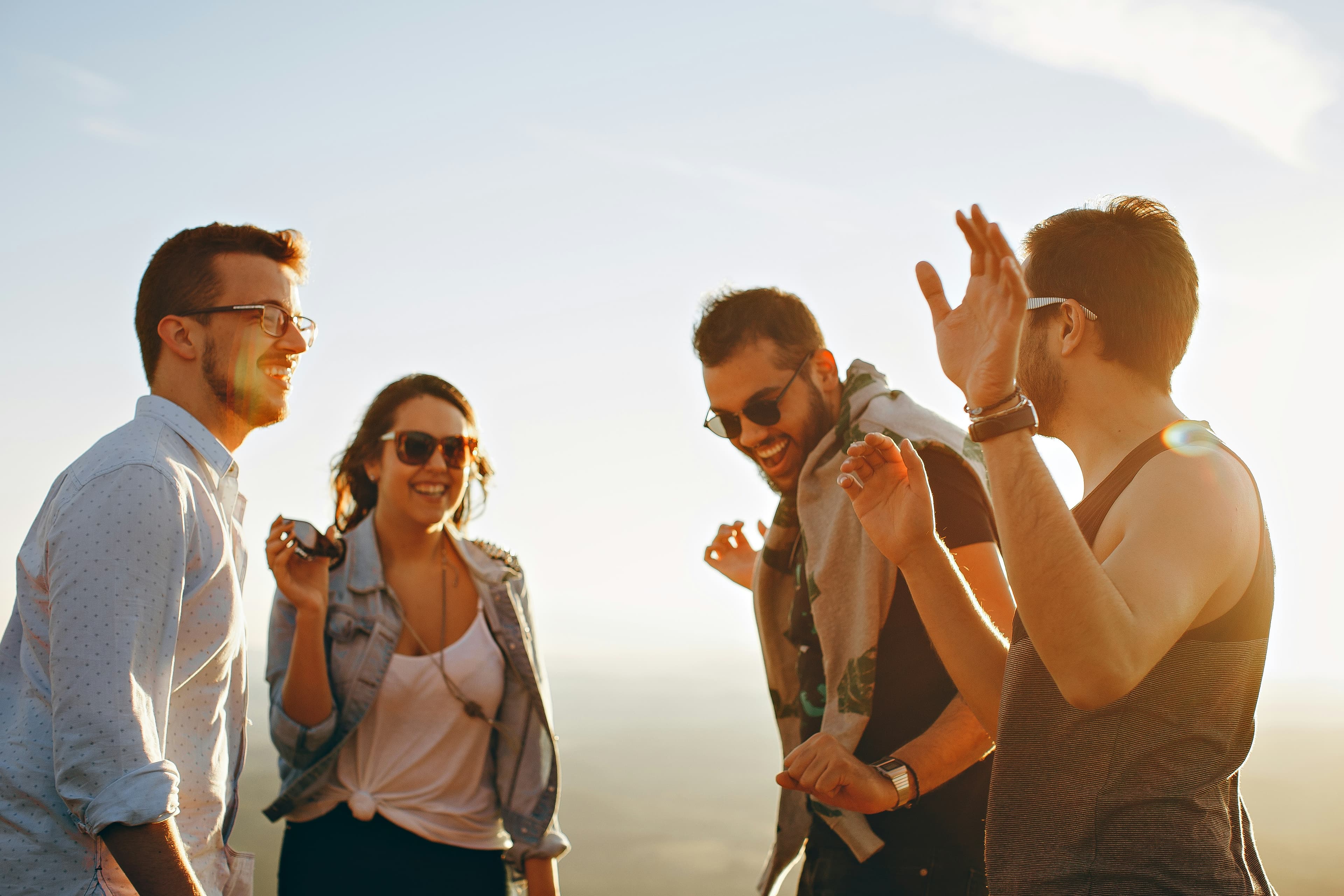 Group of young adults laughing together outdoors in golden light
