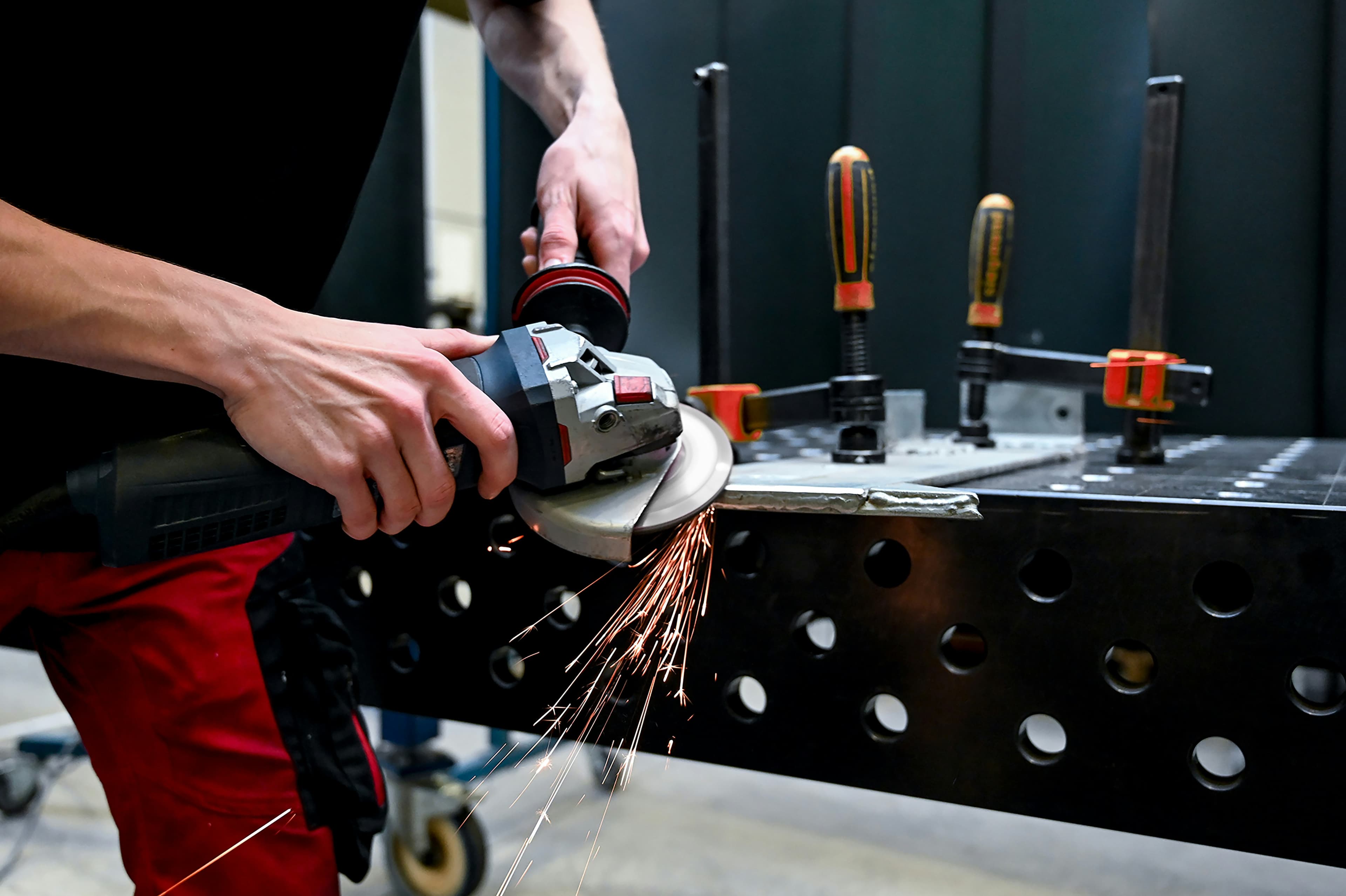 Hands using angle grinder with sparks flying